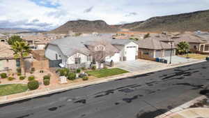 View of front facade with a residential view, a mountain view, stucco siding, stone siding, and solar panels