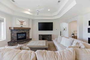 Carpeted living room with a fireplace, a ceiling fan, arched walkways, and recessed lighting