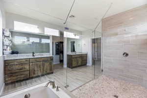 Full bath with two vanities, a stall shower, and a walk in closet