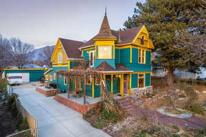 Victorian home with a shingled roof, covered porch, a mountain view, stone siding, and outdoor dining space