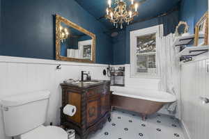 Bathroom with a freestanding bath, vanity, wainscoting, a chandelier, and tile patterned floors