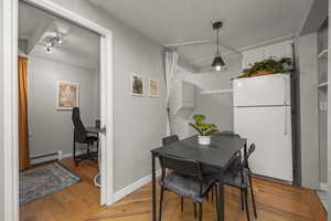 Dining area featuring light wood-style flooring, stacked washing machine and dryer, wood ceiling, a baseboard heating unit, and a desk