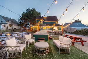 Patio terrace at dusk featuring a patio, a jacuzzi, and an outdoor living space with a fire pit