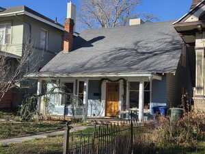 View of front of home with a chimney, a fenced front yard, covered porch, and roof with shingles