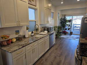 Kitchen featuring stainless steel appliances, dark stone countertops, white cabinets, healthy amount of natural light, and recessed lighting