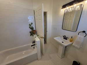 Ensuite bathroom with shower / bath combination and light tile patterned floors