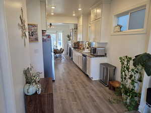 Kitchen featuring white cabinetry, stainless steel appliances, light stone countertops, dark wood-style floors, and recessed lighting