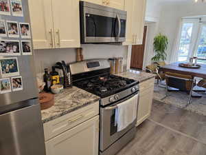Kitchen with stainless steel appliances, light stone countertops, and dark wood-style floors