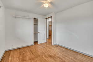Unfurnished bedroom with ceiling fan, light wood-style flooring, and a closet