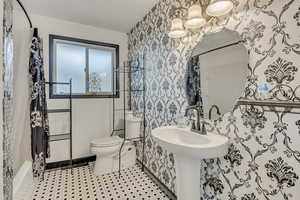 Bathroom featuring toilet and wallpapered walls