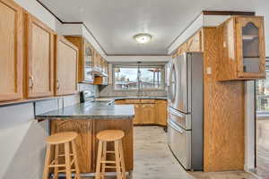 Kitchen with glass fronted cabinets, a peninsula, stainless steel appliances, a kitchen breakfast bar, and light wood-type flooring