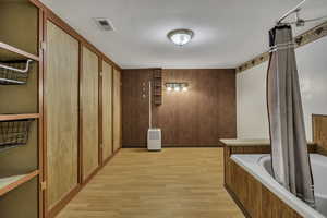 Hall featuring light wood-type flooring and wooden walls