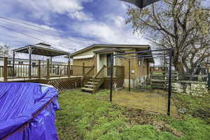 Back of property featuring a gazebo, brick siding, a wooden deck, and a patio
