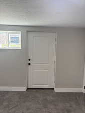 Bedroom 3 Doorway to outside light grey carpet floors and a textured ceiling