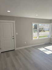 Front entry and living room featuring light laminate floors, a textured ceiling, and recessed lighting