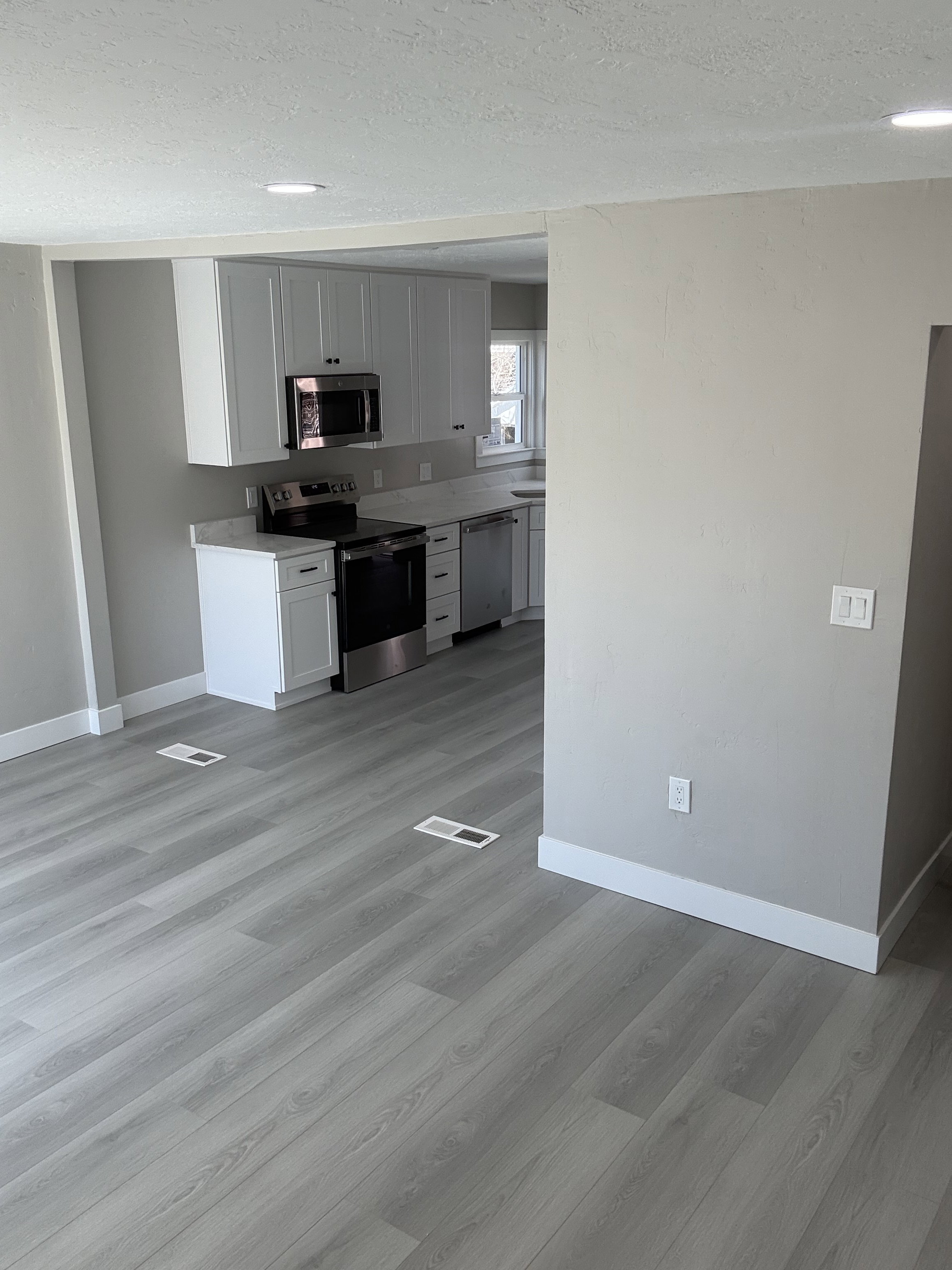 Kitchen featuring stainless steel appliances, white cabinetry, a textured ceiling, and light laminate flooring