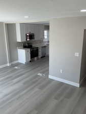 Kitchen featuring stainless steel appliances, white cabinetry, a textured ceiling, and light laminate flooring