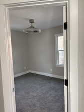 Spare room featuring dark carpet and baseboards