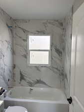 Bathroom with vanity and a combined bath / shower with marble appearance