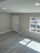 Front entry and living room featuring light laminate floors, a textured ceiling, and recessed lighting