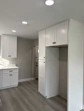 Kitchen with white cabinets, light laminate  floors, and recessed lighting