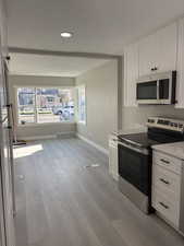 Kitchen featuring stainless steel appliances, light wood-style floors, white cabinetry, and recessed lighting