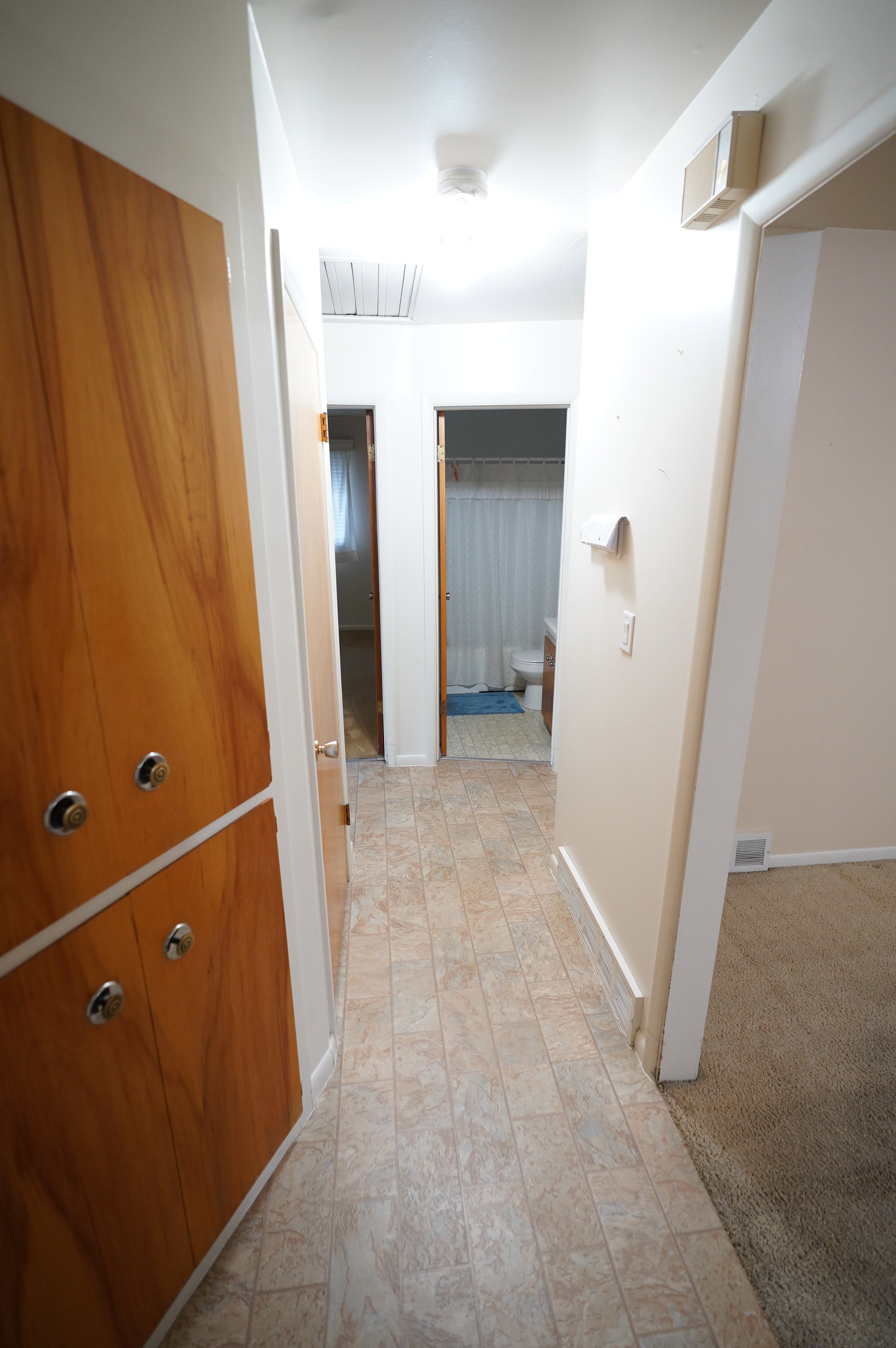 Hallway featuring light colored carpet and baseboards