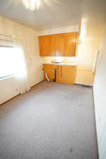 Kitchen featuring light carpet, light countertops, wood finish cabinets, wallpapered walls, and freestanding refrigerator