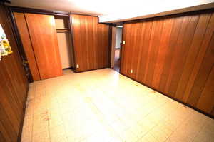 Unfurnished bedroom featuring light floors, wood walls, and a closet