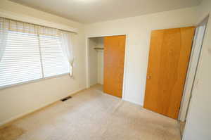 Unfurnished bedroom featuring light colored carpet and a closet