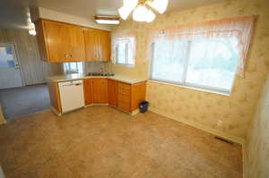 Kitchen featuring wallpapered walls, light countertops, a peninsula, white dishwasher, and ceiling fan