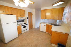 Kitchen featuring white appliances, a peninsula, light countertops, a ceiling fan, and wood finish cabinets