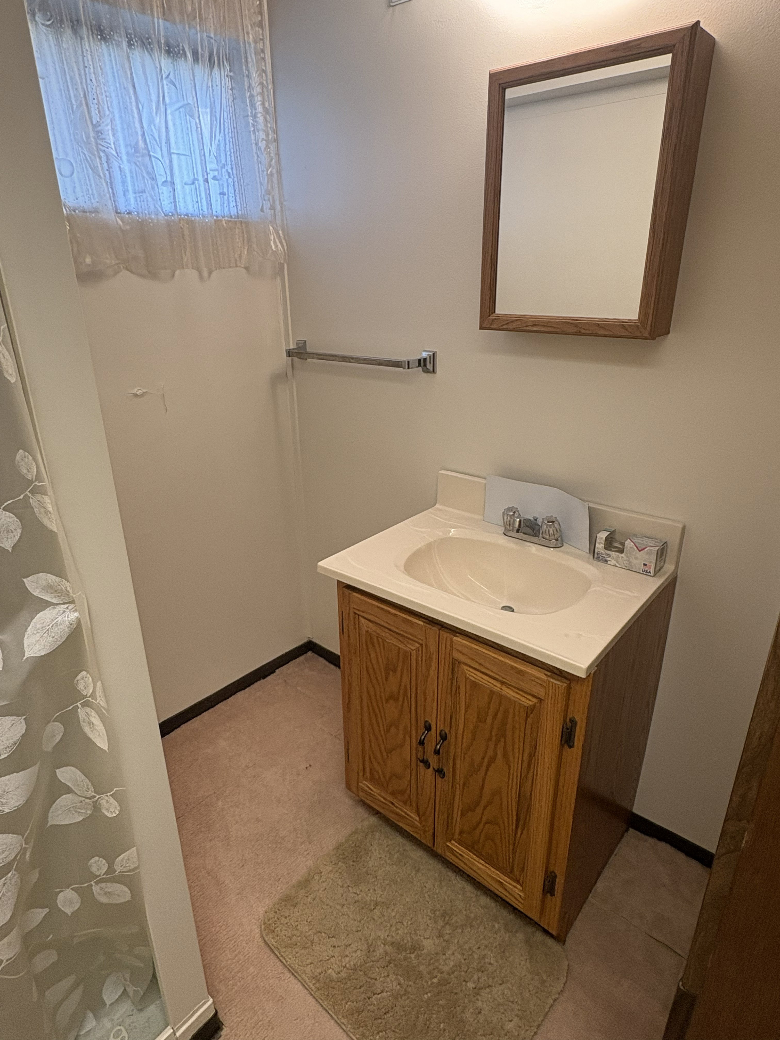 Bathroom vanity with integrated sink, wood-finish cabinetry, and framed wall mirror