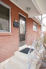 Entrance to property featuring brick siding and covered porch