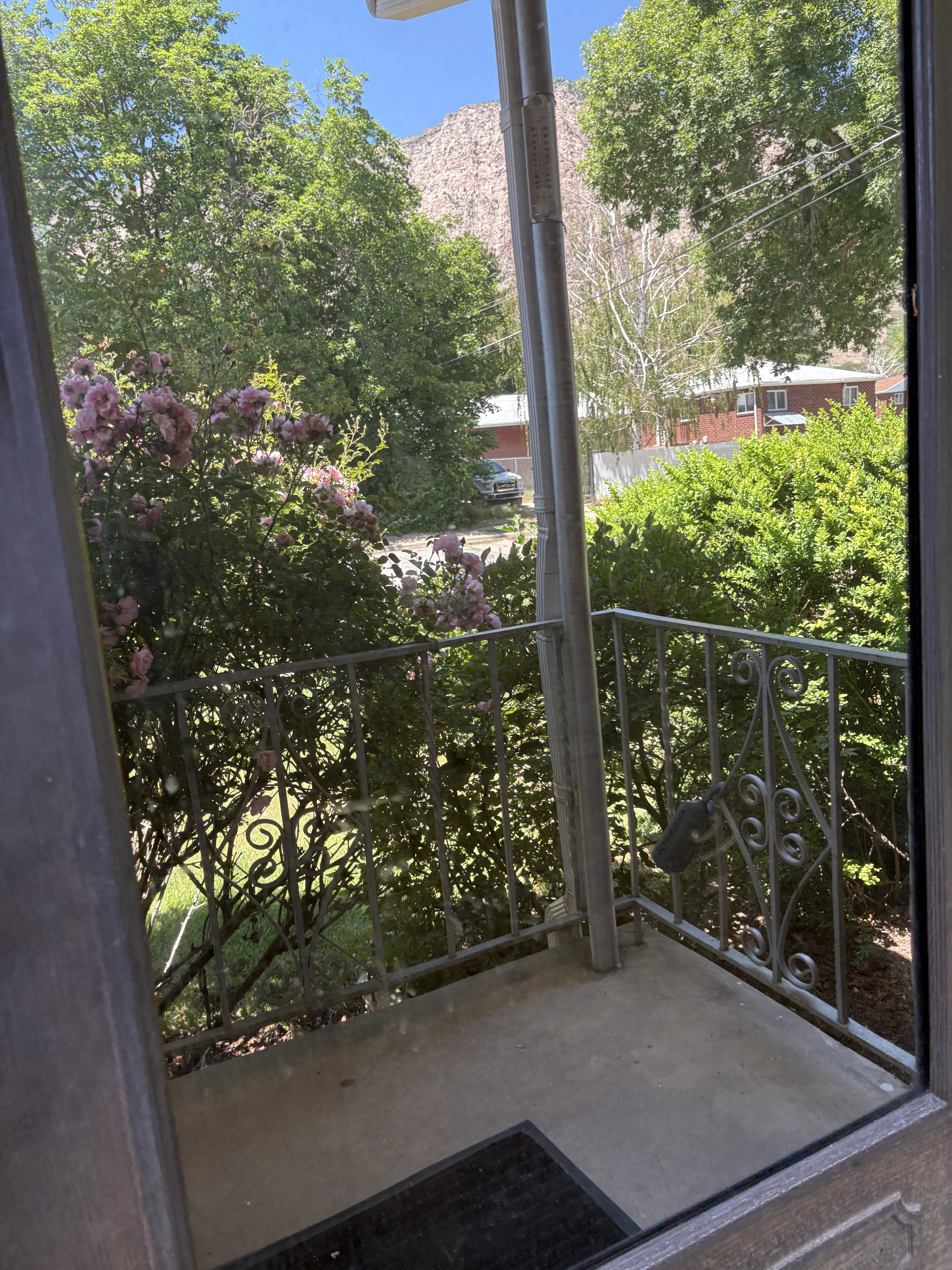 Front porch featuring an ornamental wrought iron railing and concrete flooring