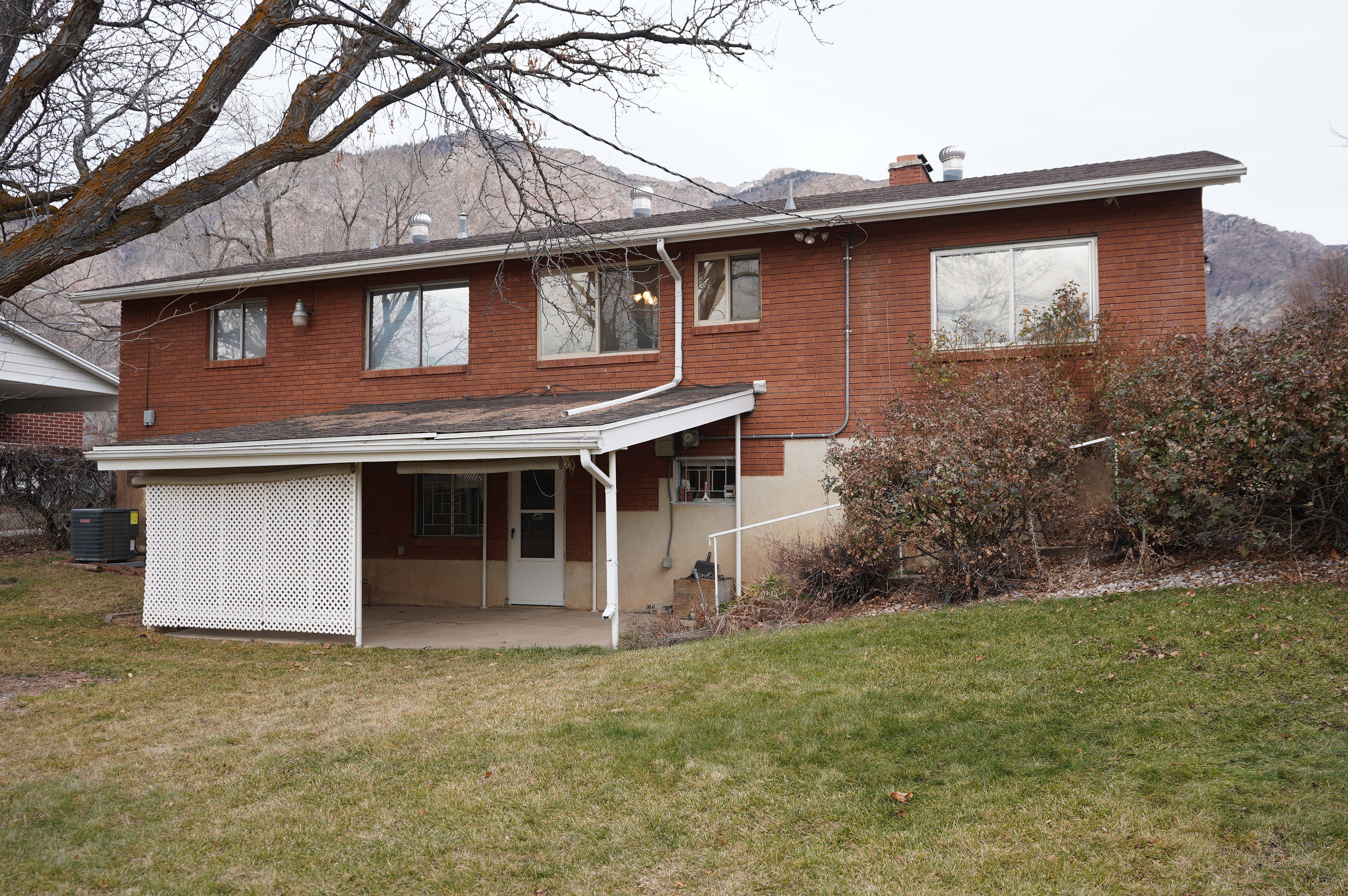 Back of house with a patio area, a chimney, a lawn, and brick siding