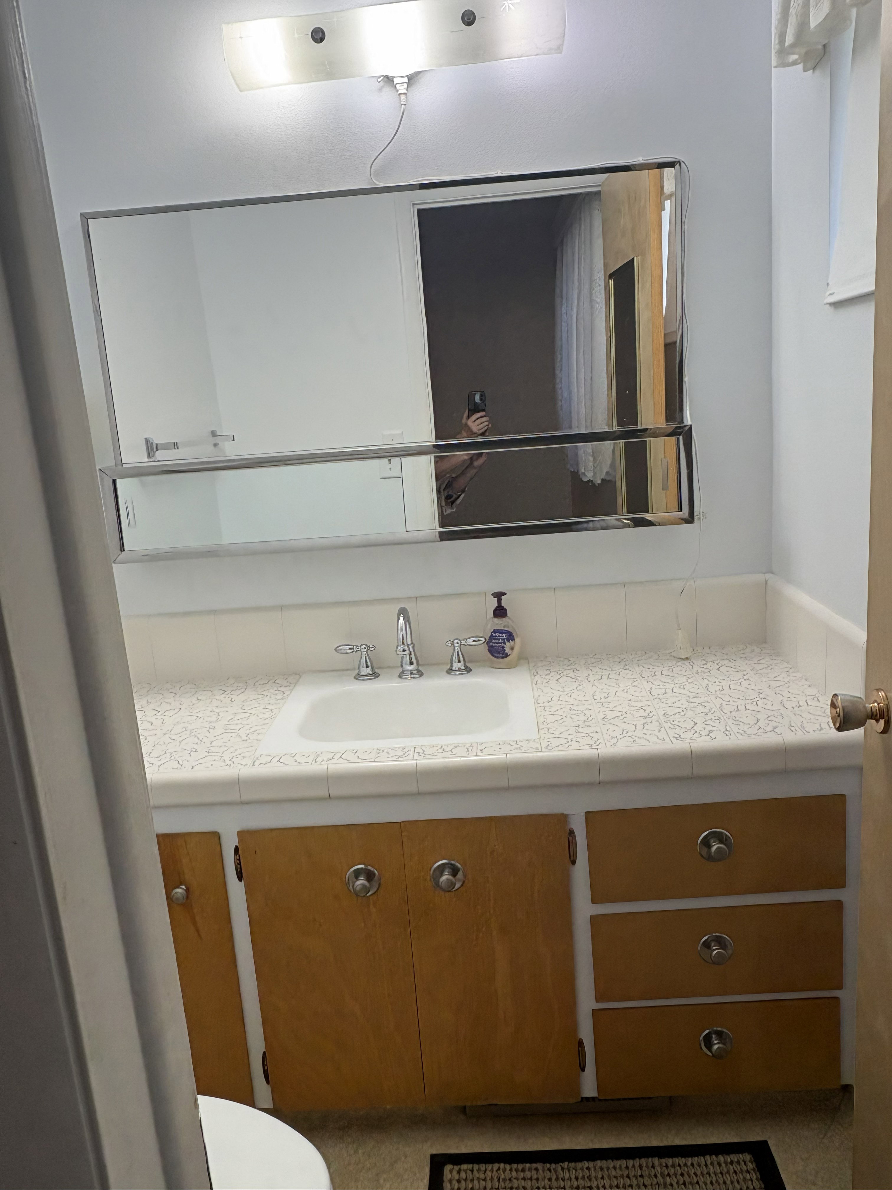 Bathroom vanity featuring a built-in sink, chrome fixtures, and a patterned countertop