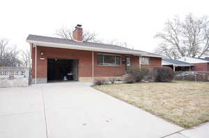 View of front of home featuring a garage, brick siding, driveway, a chimney, and a shingled roof