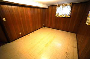 Unfurnished room with light flooring and wooden walls