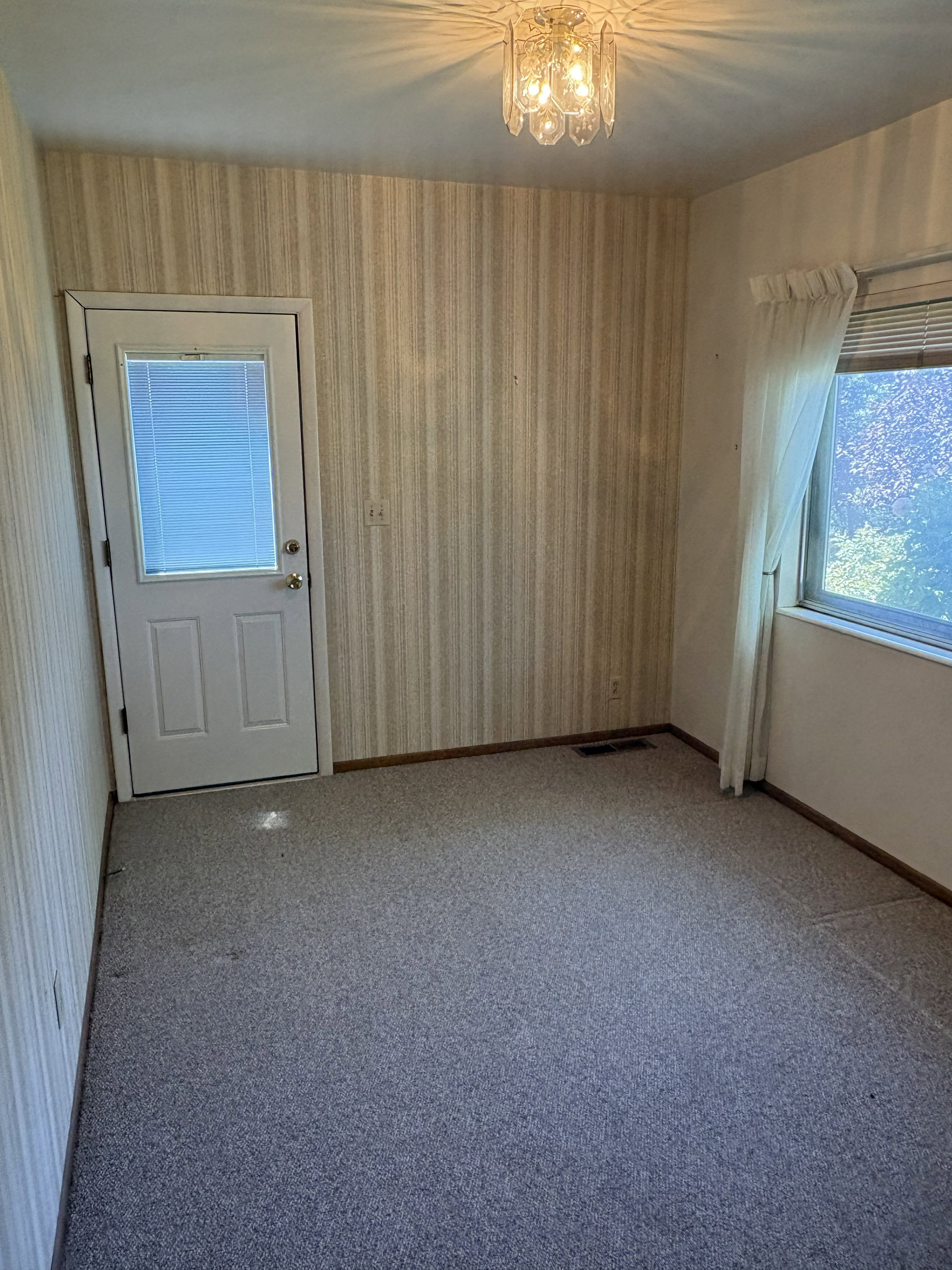 Room featuring a glass-insert door, wall-to-wall carpeting, and a window with blinds