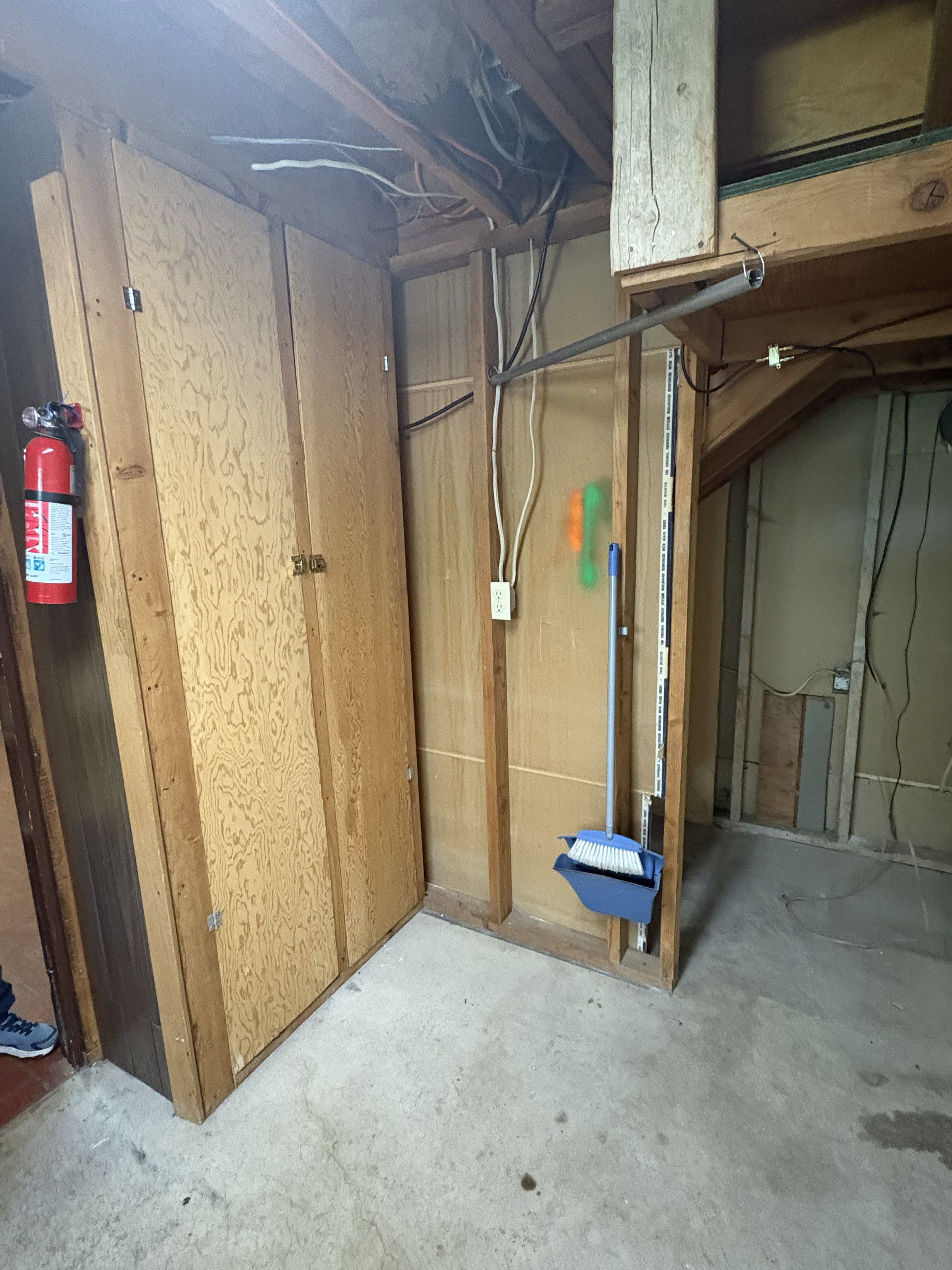 Unfinished basement space featuring exposed wooden framing, concrete flooring, and built-in storage cabinetry