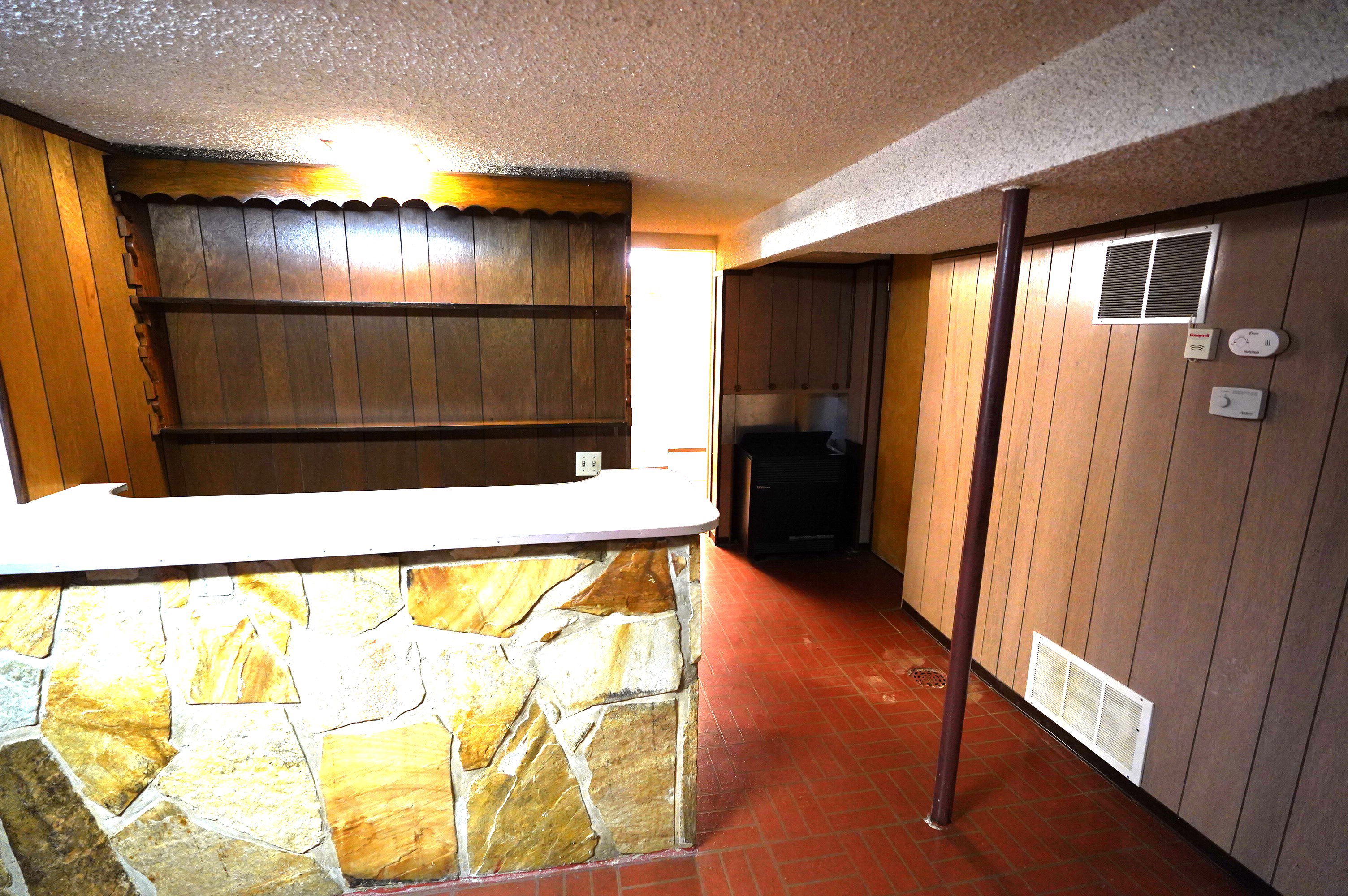 Bar featuring wood walls, brick patterned floors, and a textured ceiling