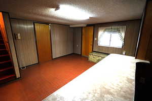 Interior space featuring a closet, wooden walls, brick patterned flooring, and a textured ceiling