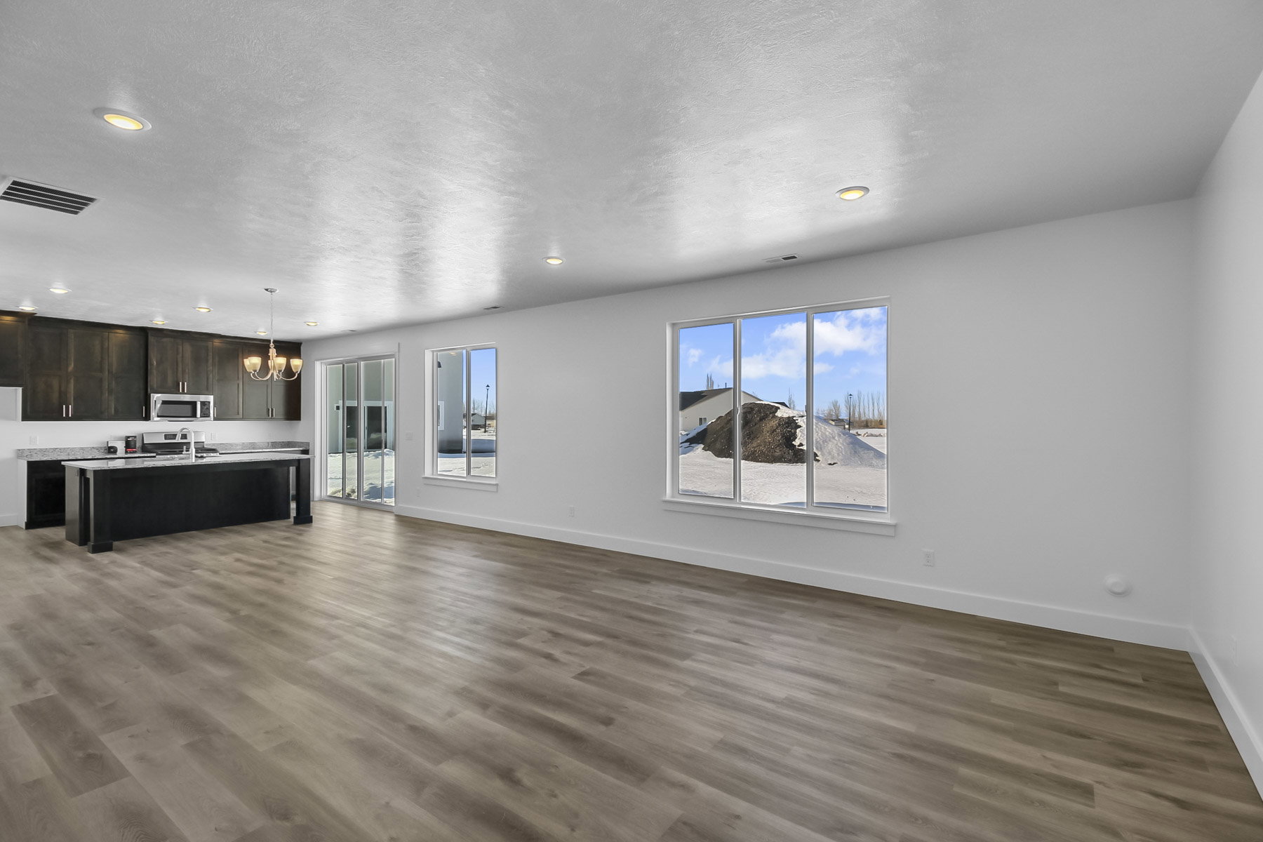 Unfurnished living room with hanging lights and dark wood-style floors