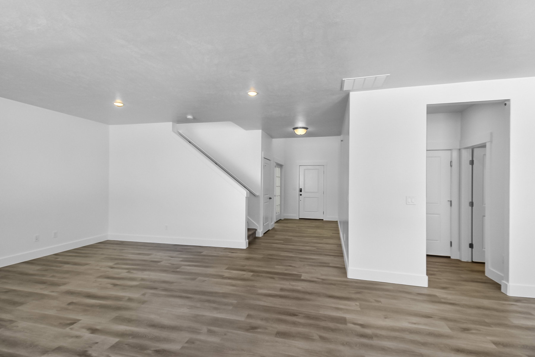 Unfurnished living room featuring stairs and light wood-style flooring