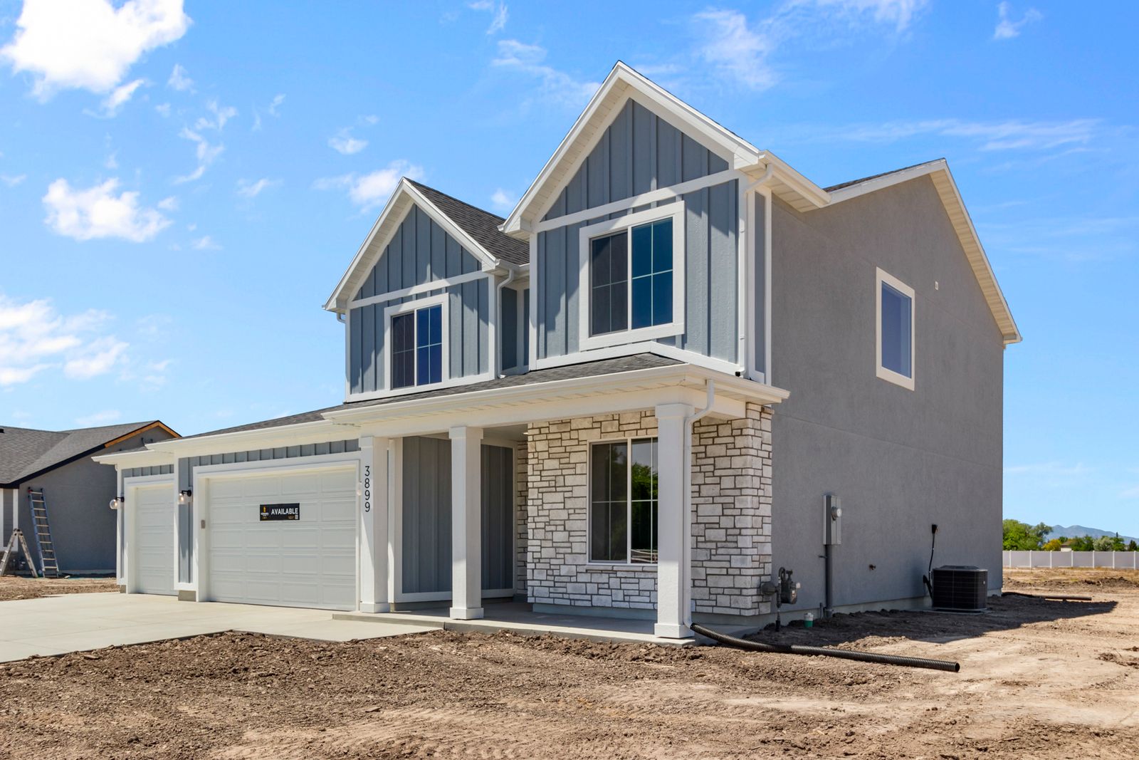 View of front facade featuring covered porch, stone siding, board and batten siding, and driveway