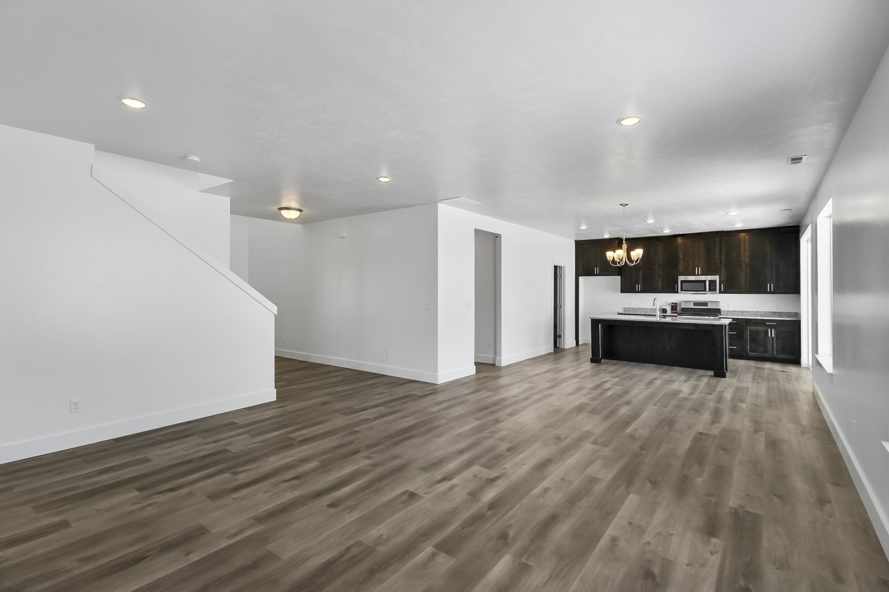 Unfurnished living room with a chandelier and dark wood-type flooring