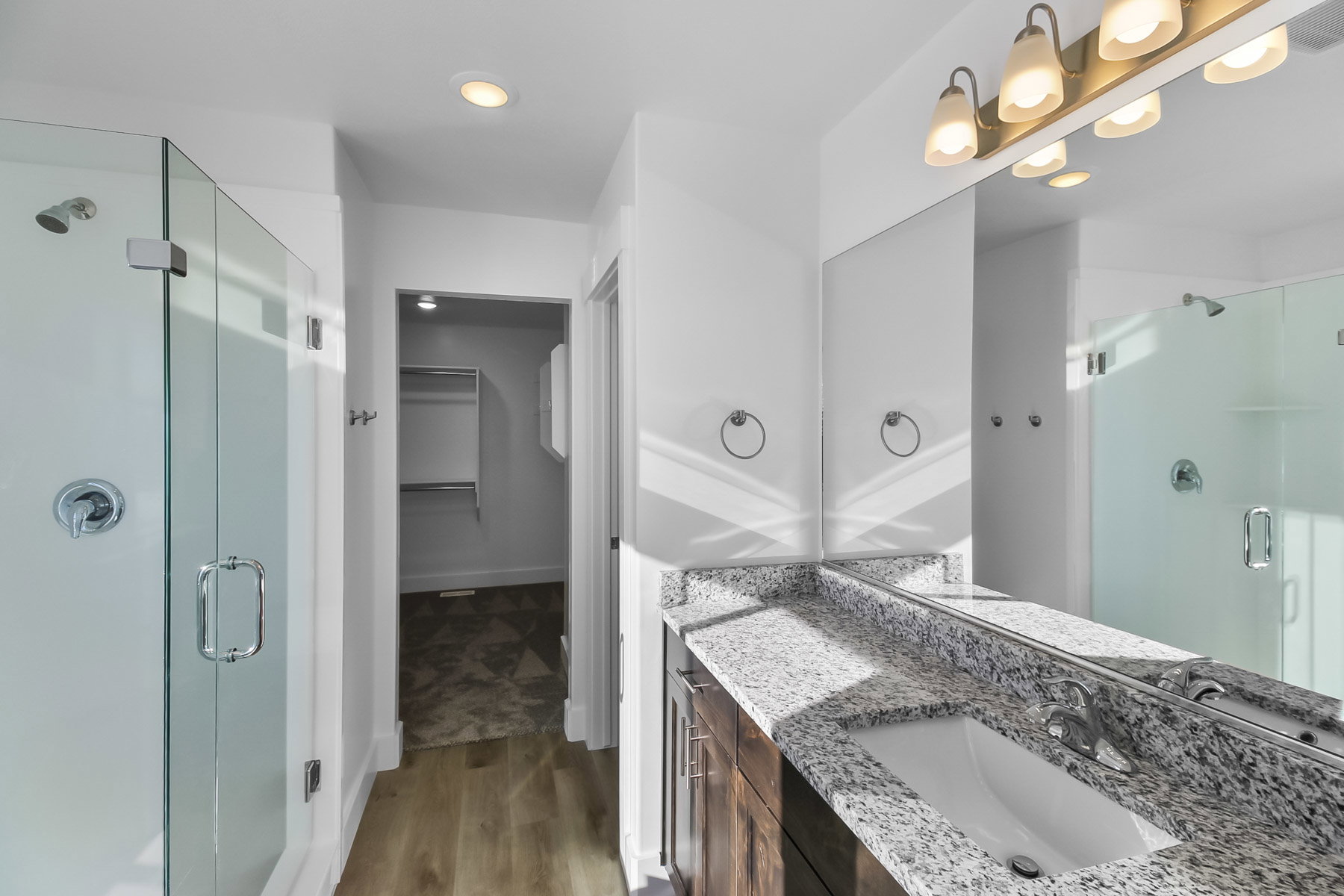 Full bathroom featuring a shower stall, vanity, a walk in closet, light wood finished floors, and recessed lighting