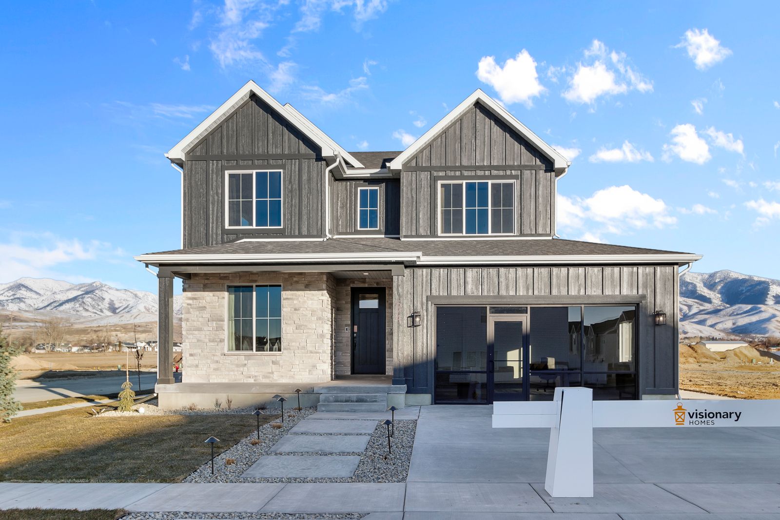 View of front facade featuring a mountain view, board and batten siding, covered porch, stone siding, and roof with shingles