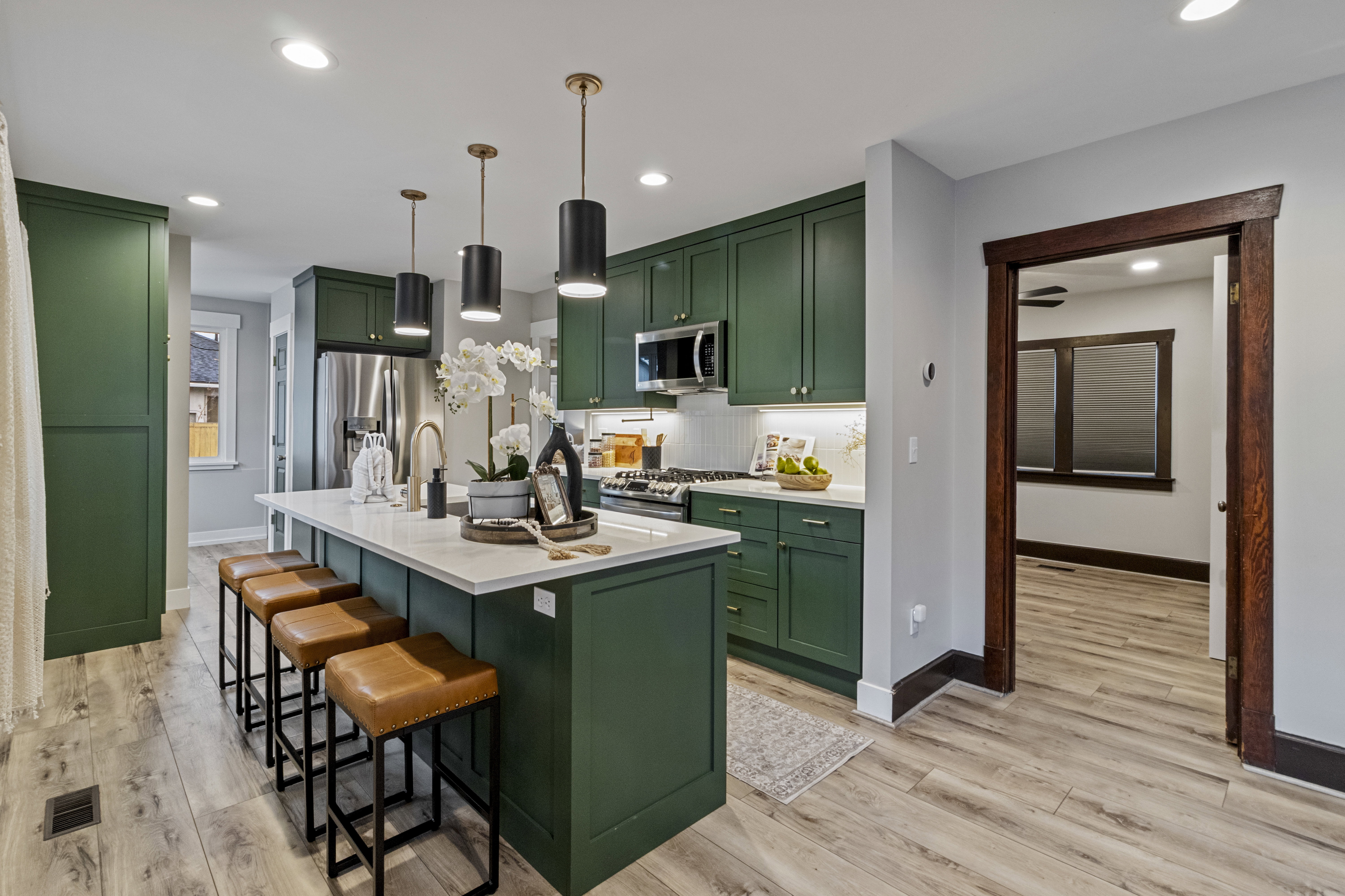 Kitchen featuring green cabinetry, light wood-type flooring, a kitchen island with sink, a breakfast bar area, and stainless steel appliances
